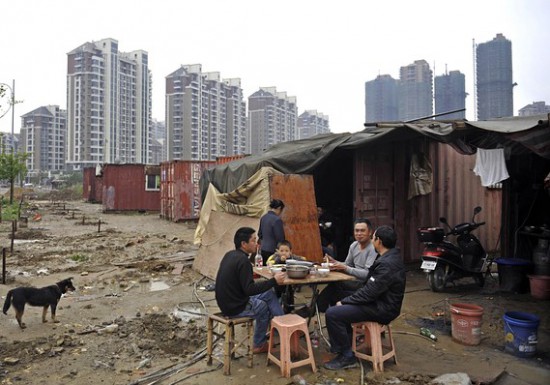 Migrant workers in the shadow of empty apartment blocks.