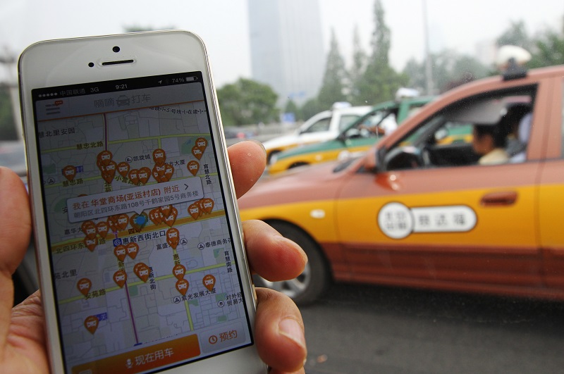 The screen of mobile phone shows the Didi Dache app is pictured with a taxi passes by in Beijing. Didi Dache has become China's most popular mobile app to call for a taxi ride. 19JUN14 Photo by Simon Song