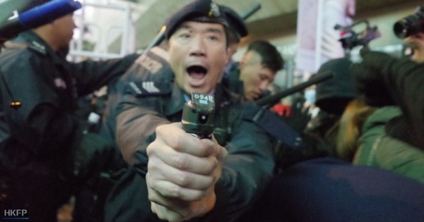 Hong Kong police office aims pepper spray at protesters.